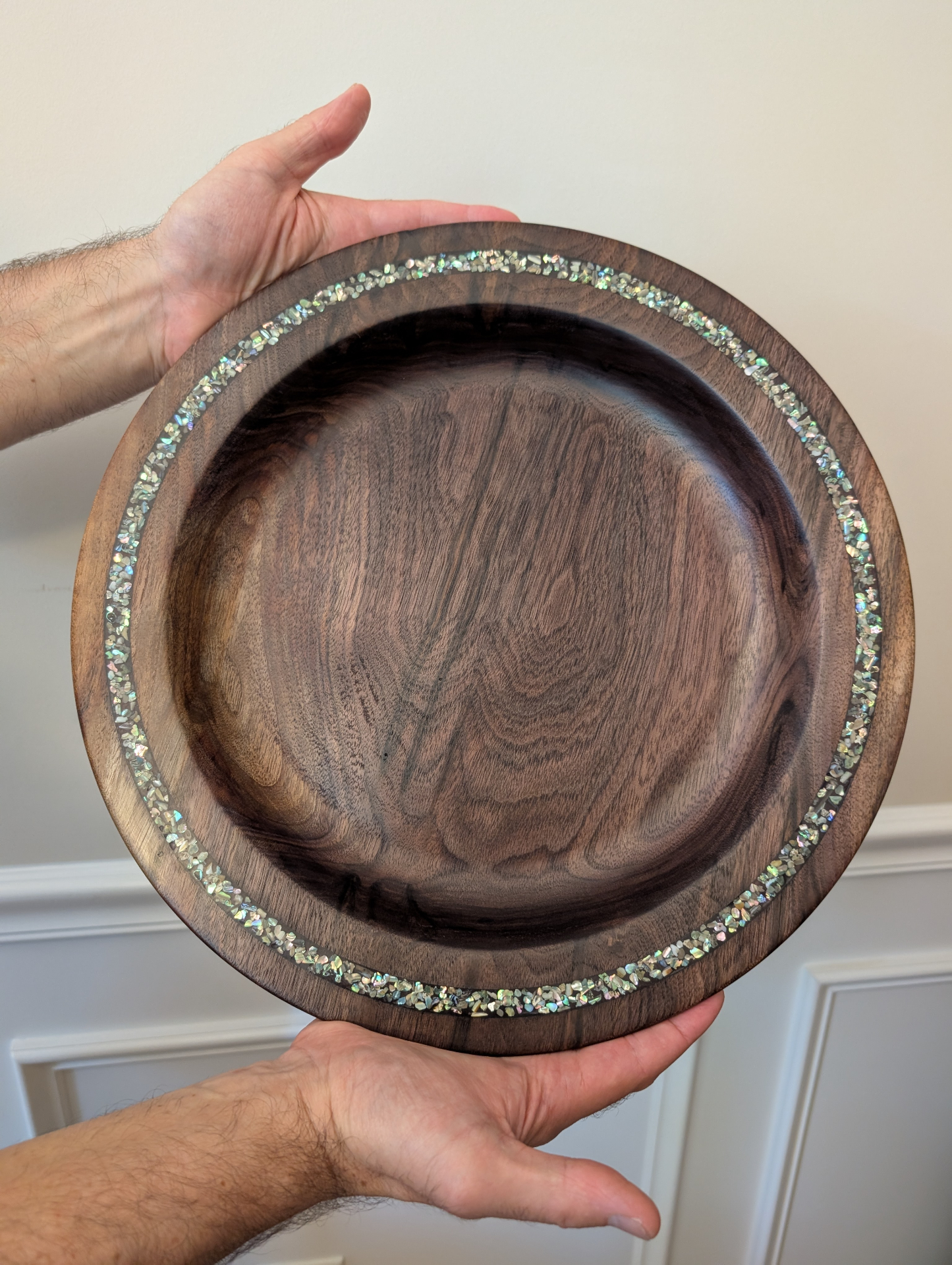 Walnut platter with abalone mother of pearl inlay held in two hands